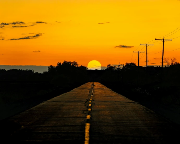 the sun is setting on the horizon of a road